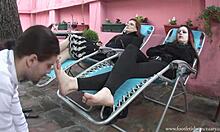 Dos chicas reclinándose y recibiendo lamidas en sus pies