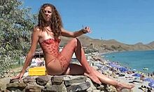 Relatório ao vivo de uma praia de nudismo, apresentando uma mulher nua