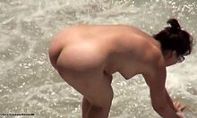 Una amateur de cabello oscuro con gafas está desnuda en la playa. ¡Mira cómo se divierten!