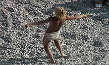 Веселая блондинка танцует на песке