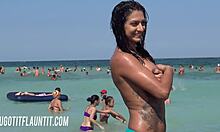 Una bruna prosperosa con un corpo fantastico mostra la sua abbronzatura su una spiaggia