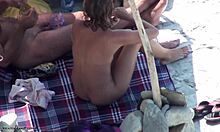 Ładna brunetka w okularach pokazuje swoje nagie ciało na plaży nudystów