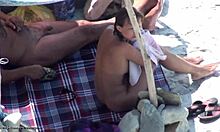Ładna brunetka w okularach pokazuje swoje nagie ciało na plaży nudystów