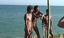 หนุ่มโสดที่มีร่างกายของ Tribal โพสท่าด้วยดาบและขี้บนชายหาด