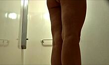 Blonda cu sânii mari face duș și își arată picioarele sexy în fața camerei