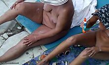 Pacar yang berkulit coklat saling menggosok punggung di pantai nudis umum