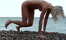 Blondin poserar helt naken på en stenig strand