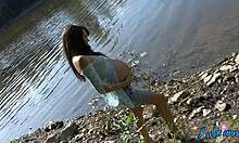 Bomba incinta che mostra il suo corpo seminudio vicino all'acqua