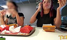 2人の性的に興奮した女性が、マクドナルドで食事をしながら胸を露出しています - プロの刺青入りの天使が登場します。