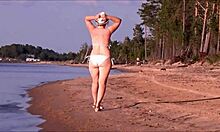 امرأة ناضجة حسي تتباهى بمنحنياتها في ملابس سباحة بيضاء.