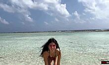 Gyllene dusch på en strand i Maldiverna för en vacker tjej som kissar